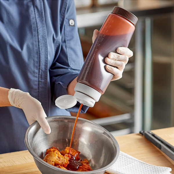 A woman pouring brown sauce from a Vollrath Traex squeeze bottle into a bowl.