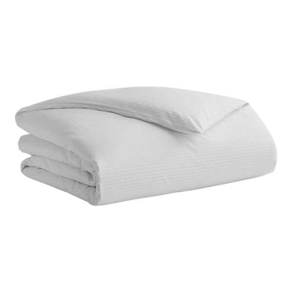 A white Garnier-Thiebaut Stanford duvet cover on a bed with folded sheets.