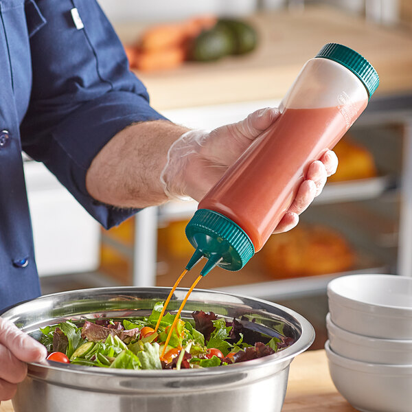 A person using a Vollrath Traex clear squeeze bottle to pour sauce into a bowl of salad.