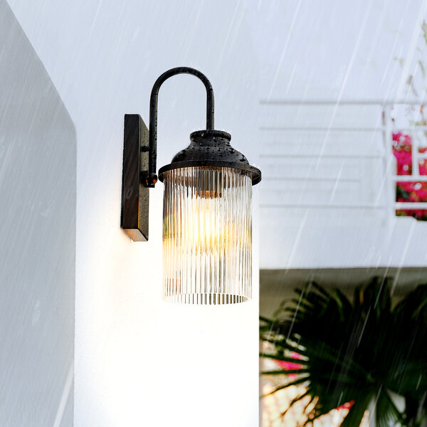 A Globe Farmhouse matte black outdoor wall sconce with a cylindrical ribbed glass shade.