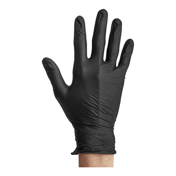 A hand wearing a black Noble Products nitrile glove on a counter.