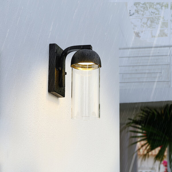 A Globe matte black wall sconce with a glass shade on a white wall.