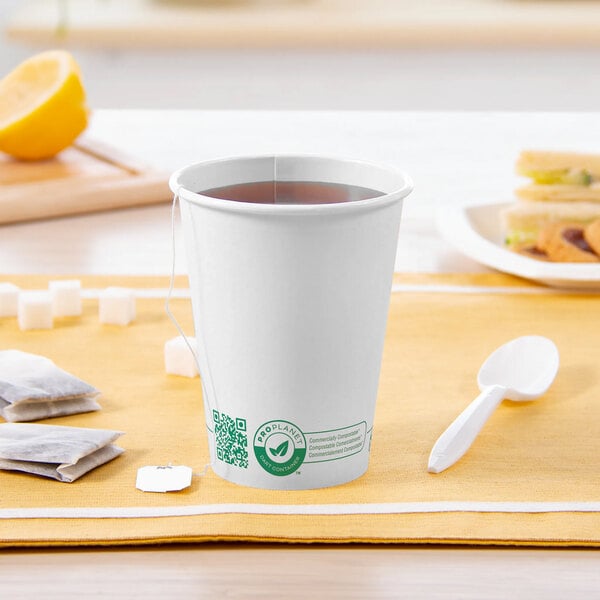 A Solo white compostable paper hot cup with a tea bag and a spoon.