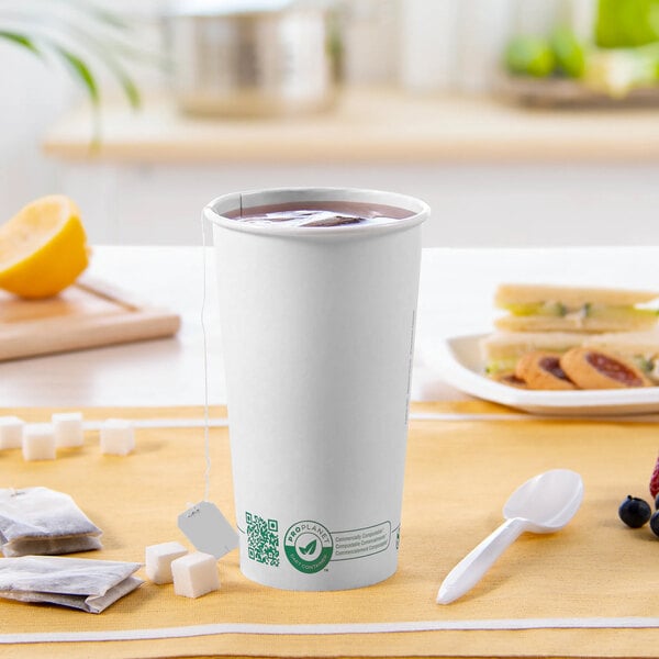 A white Solo ProPlanet paper hot cup with a tea bag and a spoon on a table.