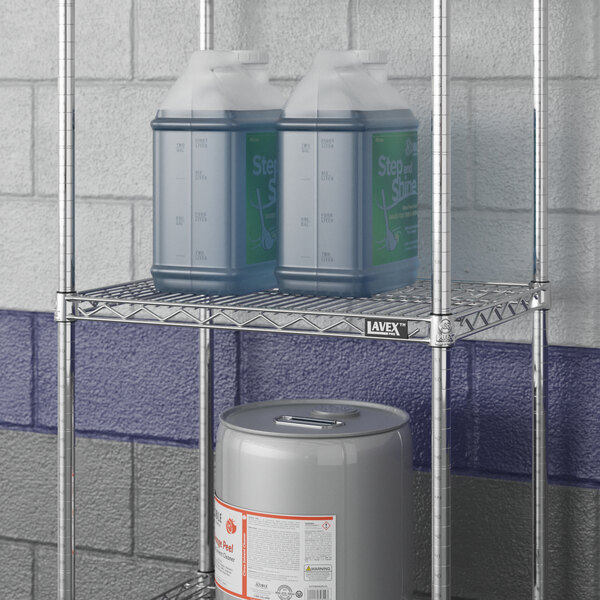 A Lavex Pro metal wire shelf with containers and a barrel on it.