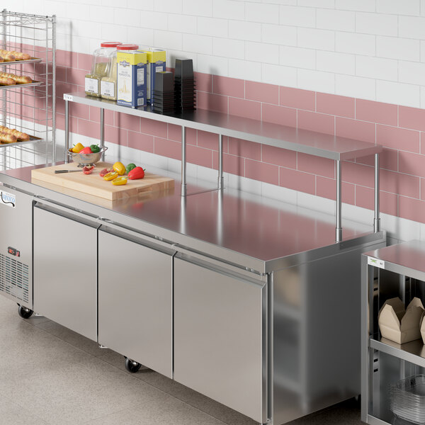 An Avantco stainless steel single deck overshelf on a counter in a commercial kitchen.