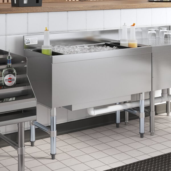 An Advance Tabco stainless steel underbar ice bin with a cold plate full of ice on a counter.