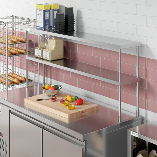 A stainless steel double deck overshelf on a counter over stainless steel shelves.