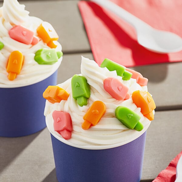 Two cups of sherbet ice cream with colorful candy on top.