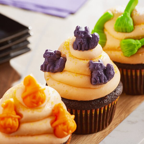 A close up of a cupcake with orange and purple frosting decorated for Halloween.