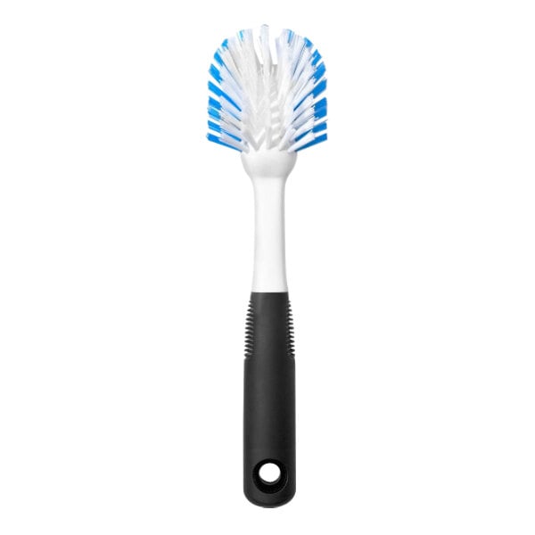 An OXO Good Grips dish brush with a blue and white handle and black and white bristles.