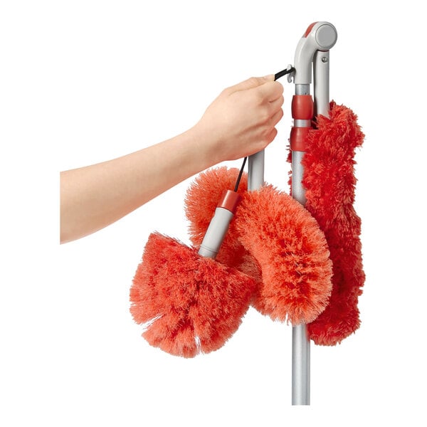 An OXO Good Grips long reach dusting kit with red dusting attachments hanging from a pole.