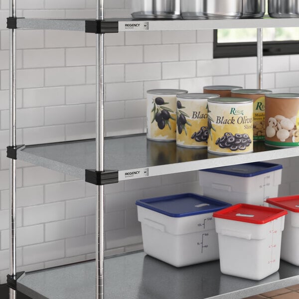 A Regency galvanized steel shelf in a kitchen with white and blue containers on it.