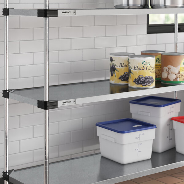 A Regency galvanized steel shelf with white and blue food containers on it.