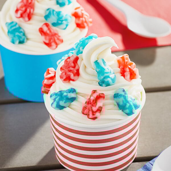 A cupcake with white frosting and Albanese red and blue gummi bears on top.