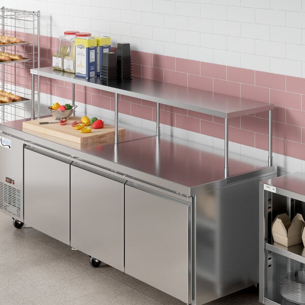 An Avantco stainless steel single deck overshelf on a counter in a commercial kitchen.