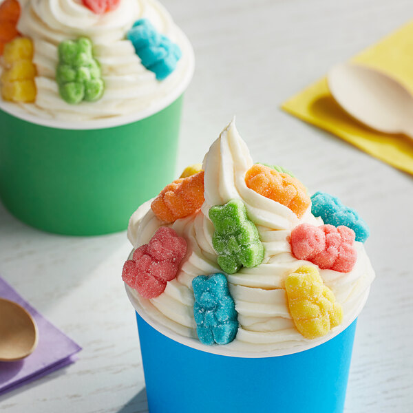 A cup of frozen yogurt with colorful gummy bears on top.