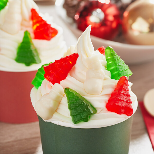 A cupcake with white frosting and Albanese gummi snowmen and trees on top.