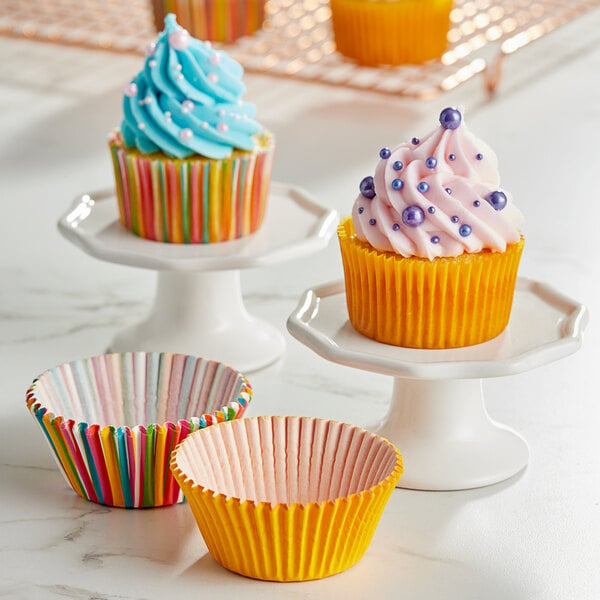 Assorted color cupcake liners on cupcakes with blue frosting and pearls.