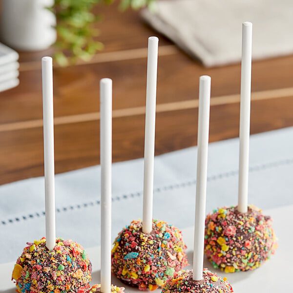 A group of four cake pops on white sticks on a plate.