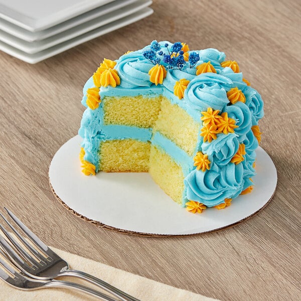 A Wilton white corrugated cake circle with a cake on top on a table.