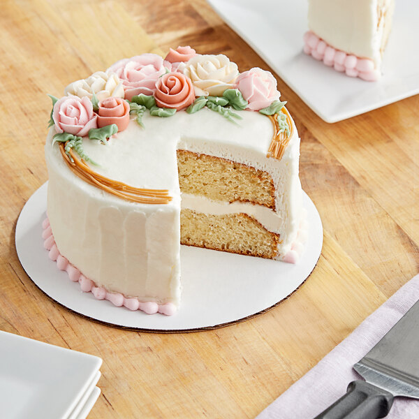 A Wilton white cake circle with a cake decorated with flowers on top.