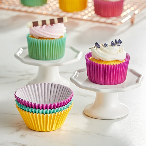 A group of cupcakes with assorted jewel tone cupcake liners on a stand.