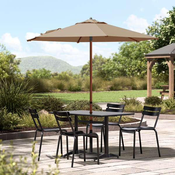 A Lancaster Table & Seating woodgrain umbrella on a patio table with chairs.