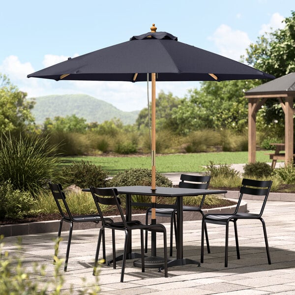 A Lancaster Table & Seating Indigo Blue Bamboo Umbrella on an outdoor patio table with chairs.