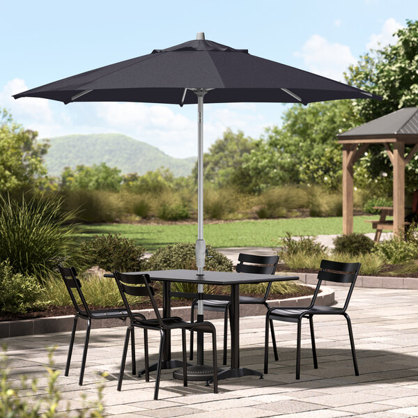 A table and chairs with a navy umbrella on an outdoor patio.