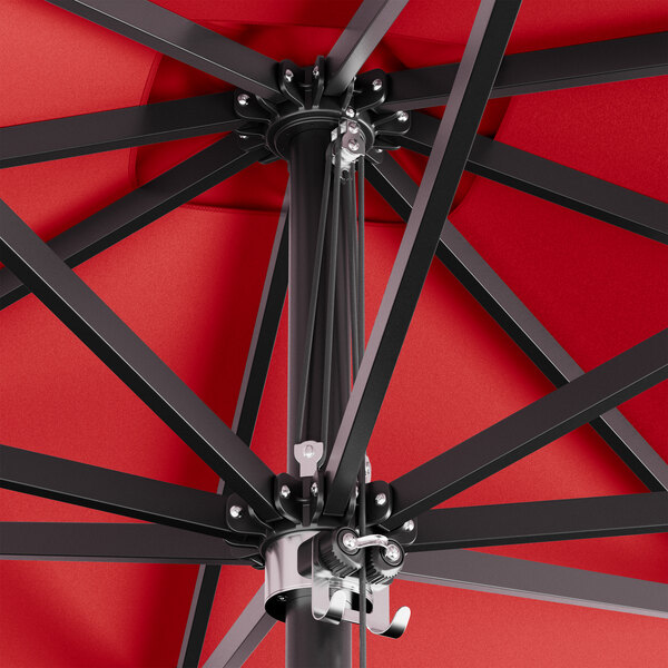 A close up of a red Lancaster Table & Seating square umbrella with black metal poles.