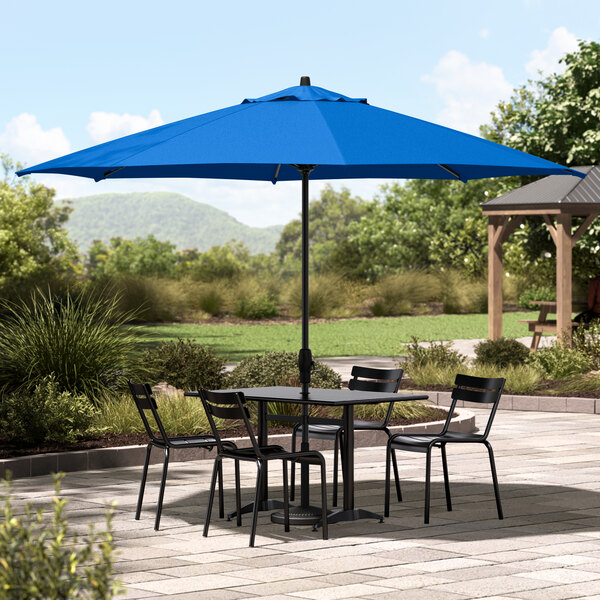 A Lancaster Table & Seating Cobalt Blue Umbrella on a black outdoor patio table.