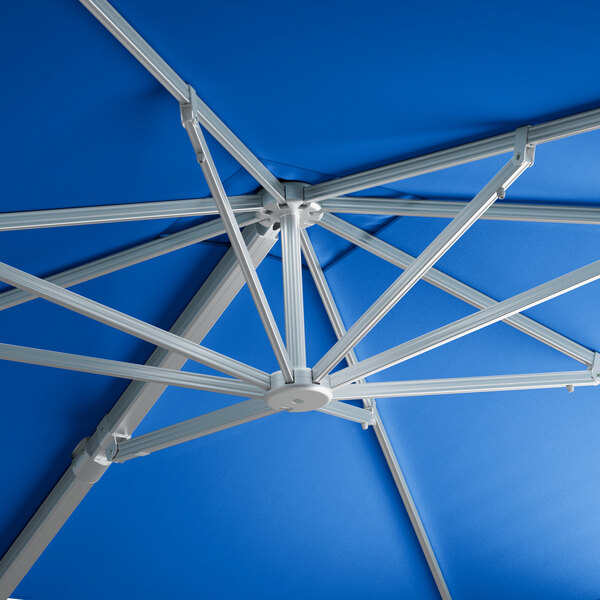 A close up of a blue Lancaster Table & Seating cantilever umbrella with silver metal rods.