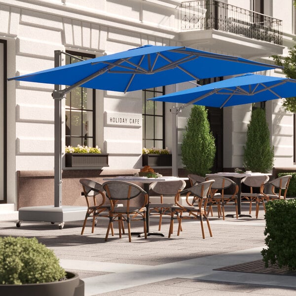 A patio with tables and blue Lancaster Table & Seating umbrellas.