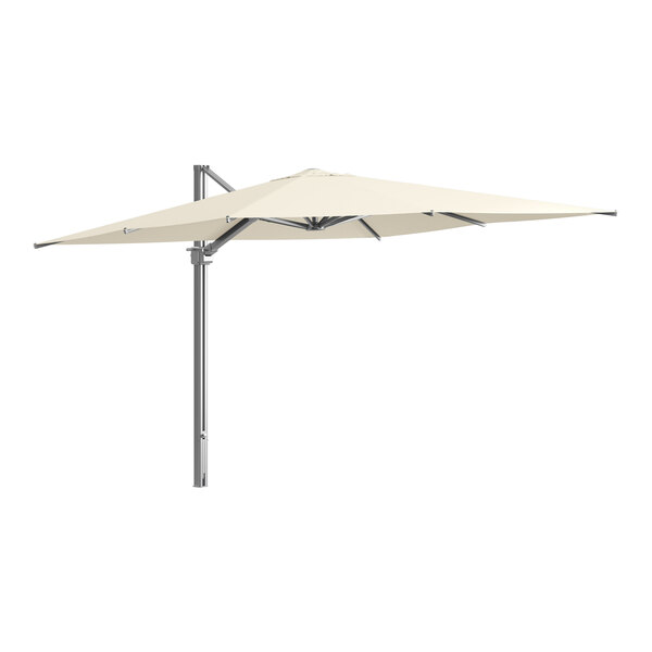 A Lancaster Table & Seating ivory cantilever umbrella on a metal pole.