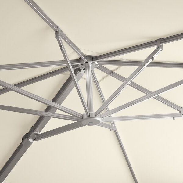 The metal structure of a Lancaster Table & Seating ivory cantilever umbrella.