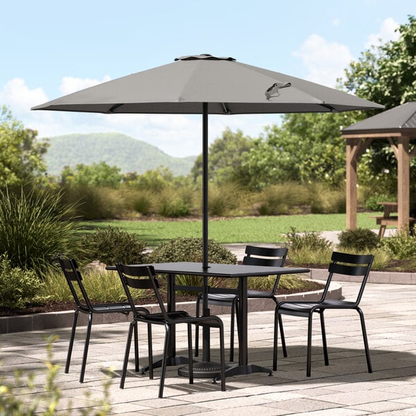 A Lancaster Table & Seating pewter gray umbrella on a table with chairs on a patio.