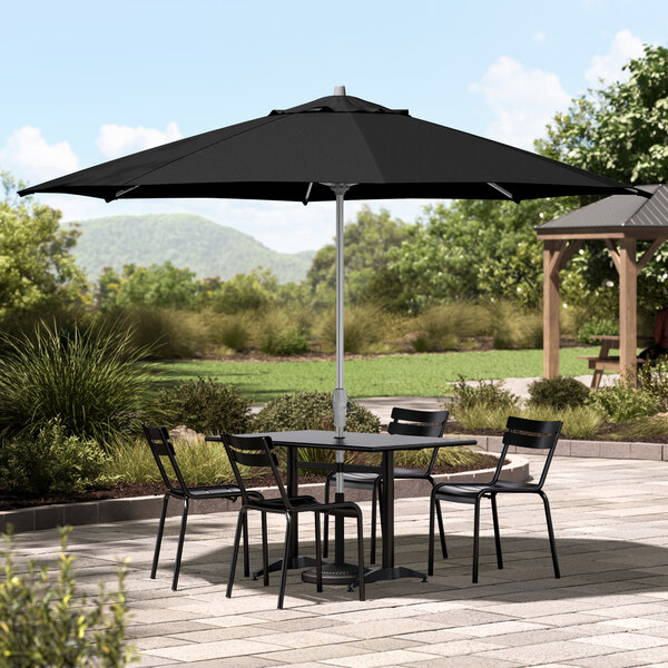 A black table and chairs under a Lancaster Table & Seating black umbrella on a patio.