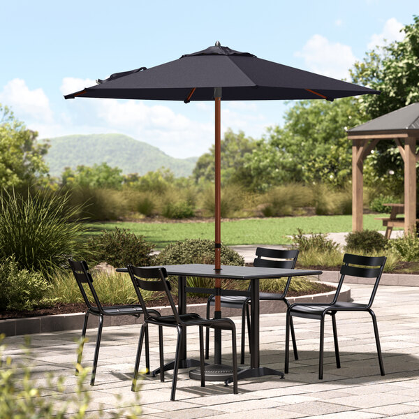 A Lancaster Table & Seating navy umbrella on a round table with chairs outside.