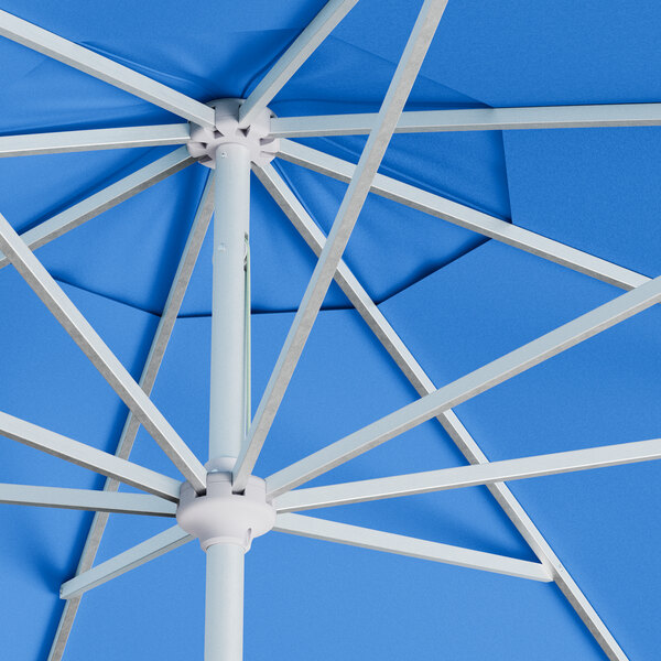 A close up of a blue Lancaster Table & Seating umbrella with a silver pole.