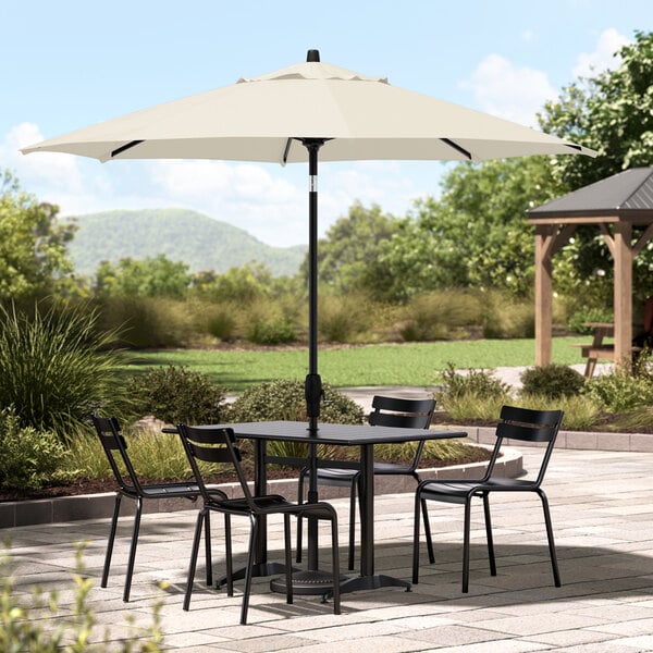 A table with chairs under a white Lancaster Table & Seating umbrella on a patio.