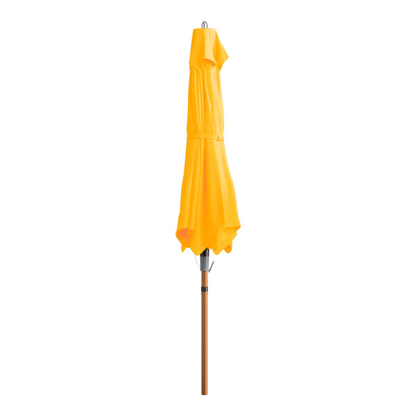 A yellow umbrella on a woodgrain pole.