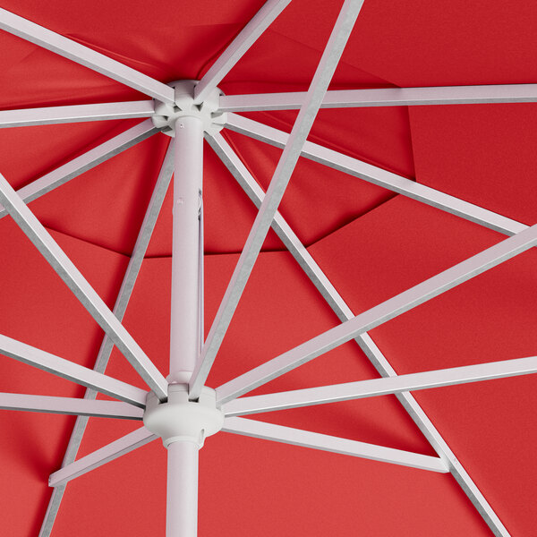 A close up of a red Lancaster Table & Seating umbrella with a silver pole.