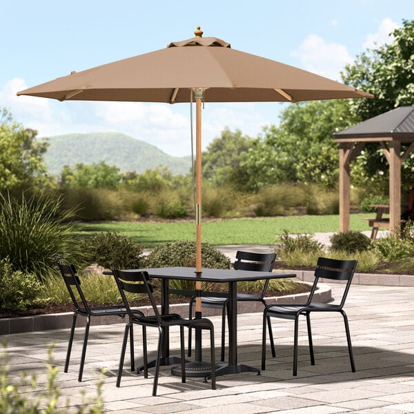 A Lancaster Table & Seating umbrella with a table and chairs on an outdoor patio.