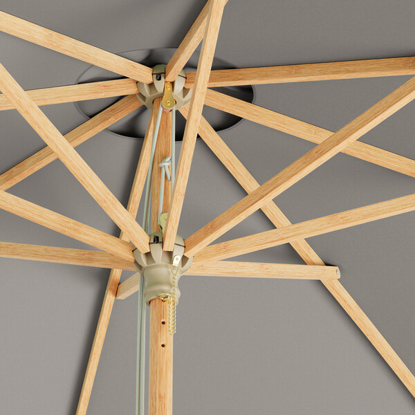 A Lancaster Table & Seating round grey bamboo umbrella with a metal pole and pulley lift.