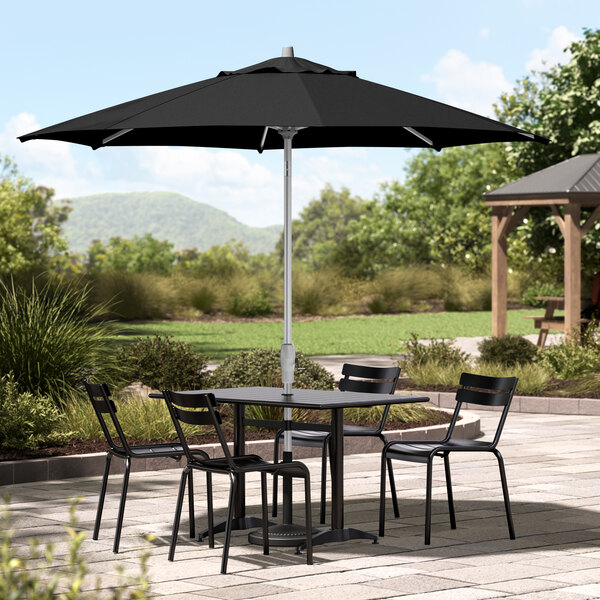 A patio table with chairs under a black Lancaster Table & Seating umbrella.