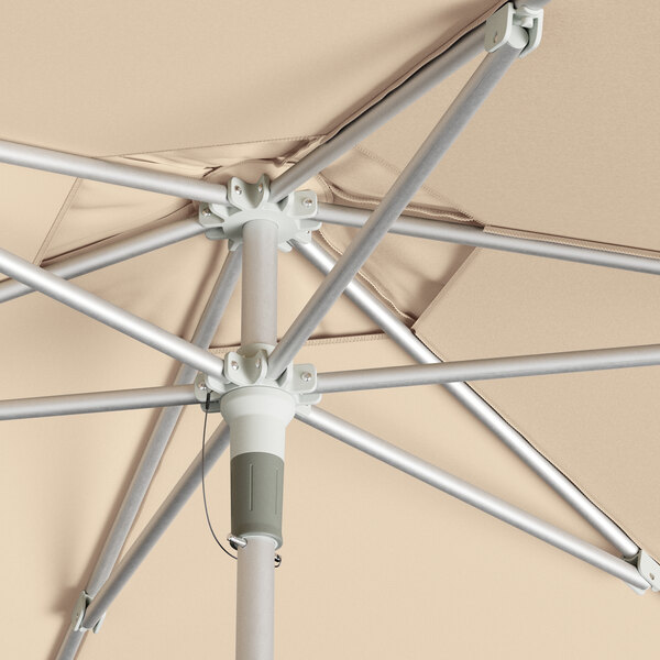 A Lancaster Table & Seating round silver aluminum umbrella open on a metal pole.