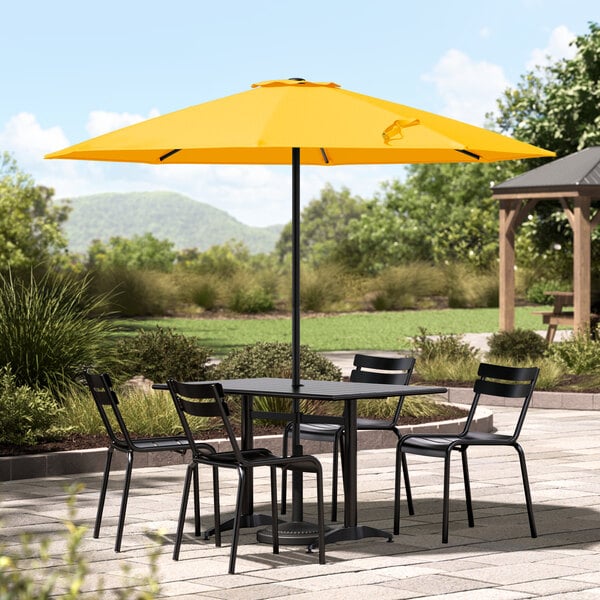 A Lancaster Table & Seating canary yellow umbrella on a round patio table.