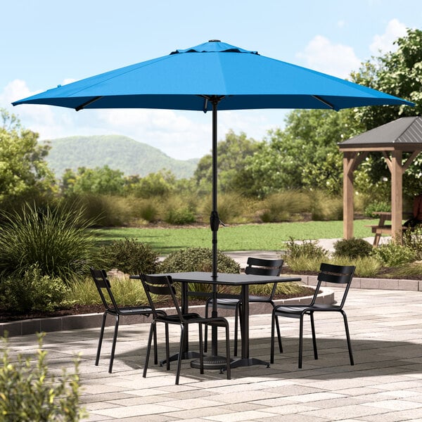 A Lancaster Table & Seating blue umbrella on a patio table.