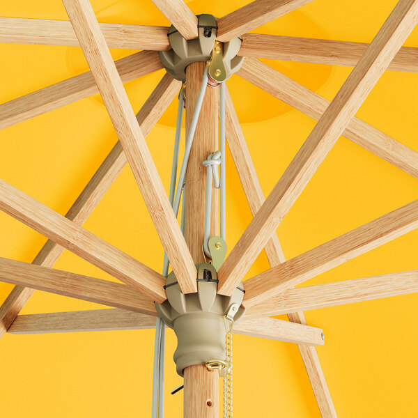 A Lancaster Table & Seating round yellow bamboo umbrella with a pulley lift.